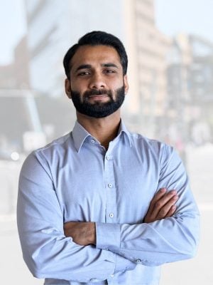 Confident man with arms crossed in urban setting.